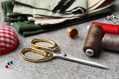 Photo of Scissors, spools of threads and sewing tools on light textured table