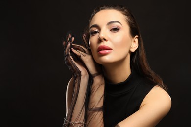 Photo of Portrait of beautiful young woman in elegant evening gloves on black background