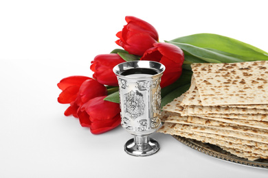 Passover matzos, silver goblet and flowers on white background. Pesach celebration
