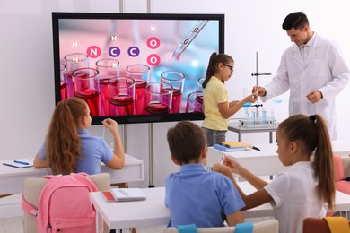 Teacher and pupils in classroom with interactive board during practical lesson