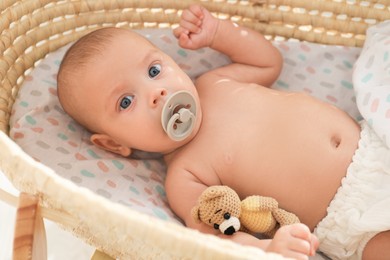 Cute little baby with pacifier and toy bear lying in cradle