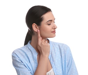 Young woman pointing at her ear on white background