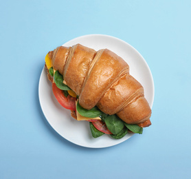 Tasty vegetarian croissant sandwich on light blue background, top view