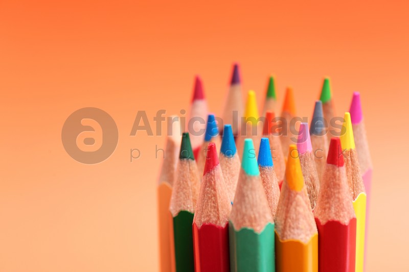 Different color pencils on coral background, closeup. Space for text