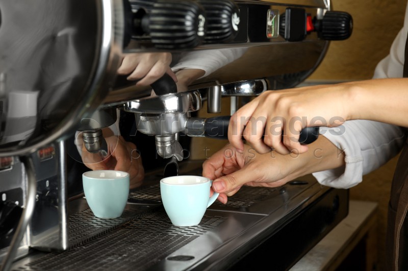 Barista making espresso using professional coffee machine, closeup