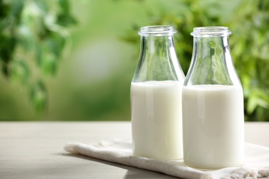 Fresh milk on wooden table against blurred background, space for text