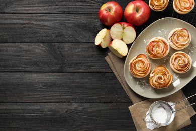 Freshly baked apple roses on dark wooden table, flat lay. Space for text