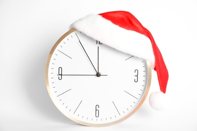 Photo of Clock with Santa hat showing five minutes until midnight on white background. New Year countdown