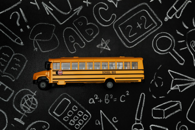 Yellow school bus and doodles on chalkboard, top view. Transport for students