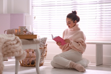 Beautiful young woman with book relaxing at home. Cozy atmosphere
