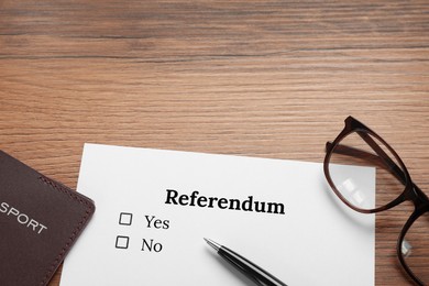 Referendum ballot with pen, passport and glasses on wooden table, flat lay. Space for text