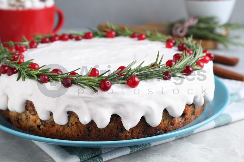 Photo of Traditional Christmas cake decorated with rosemary and cranberries on light grey marble table, closeup