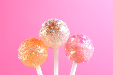 Photo of Sweet lollipops with glitter sprinkles on pink  background
