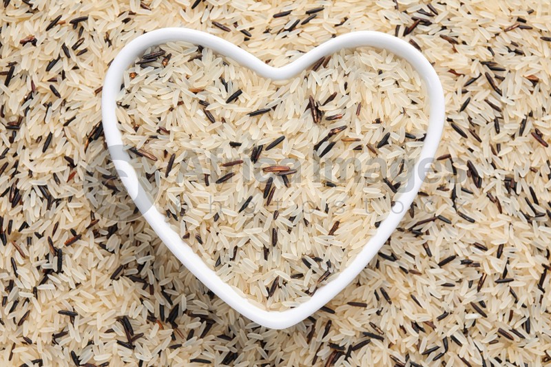 Mix of brown and polished rice with heart shaped bowl, top view