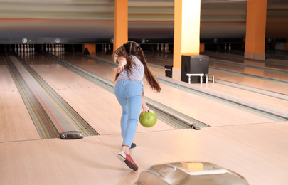 Preteen girl throwing ball at bowling club