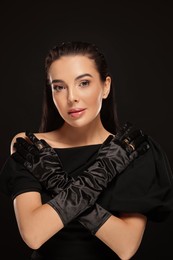 Photo of Portrait of beautiful young woman in elegant evening gloves on black background