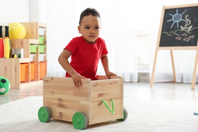 Cute little African-American child playing in kindergarten, space for text. Indoor activity