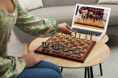 Woman playing chess with partner via online video chat in living room, closeup