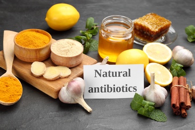 Different fresh products and card with phrase Natural Antibiotic on black table