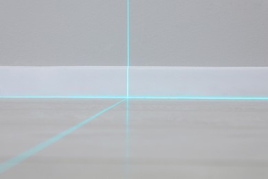 Cross lines of laser level on wall and floor indoors