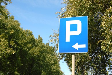 Photo of Road sign Parking Left near trees outdoors. Space for text