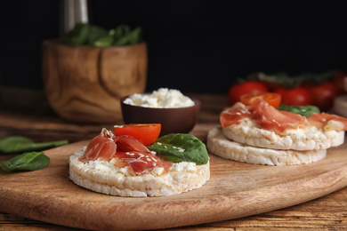Puffed rice cakes with prosciutto, tomato and basil on wooden board