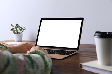 Woman working on laptop at wooden table, closeup. Mockup for design
