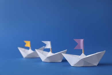 Handmade paper boats with flags on blue background. Origami art