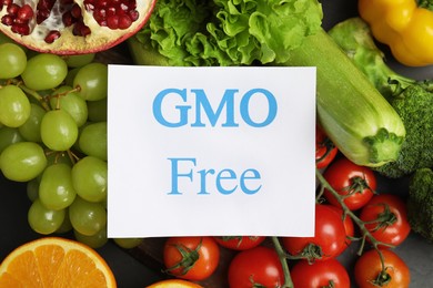 Tasty fresh GMO free products and paper card on table, top view