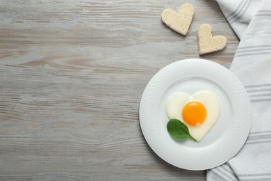 Photo of Tasty breakfast with heart shaped fried egg served on white wooden table, flat lay. Space for text