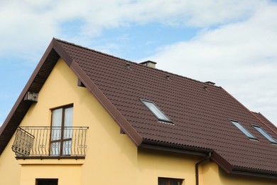 Modern house with brown roof against cloudy sky