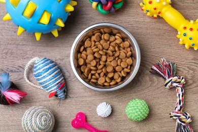 Flat lay composition with different pet toys and feeding bowl on wooden background