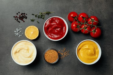 Flat lay composition with ketchup, mustard, mayonnaise and ingredients on grey table