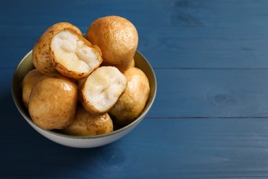 Photo of Bowl of tasty whole baked potatoes on blue wooden table, closeup. Space for text