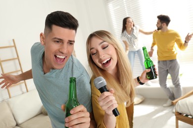 Happy couple singing karaoke with friends at home