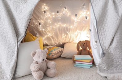 Play tent with toys and pillows indoors, closeup. Modern children's room interior