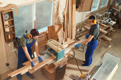 Professional carpenters working together in shop, view from above