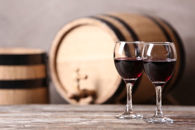 Glasses with red wine and blurred barrel on background