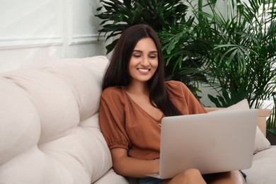Photo of Beautiful woman using laptop on sofa in living room. Interior design