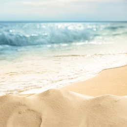 Ocean waves rolling on sandy beach, closeup view