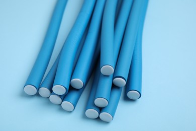 Photo of Curling rods on turquoise background, closeup. Hair styling tool