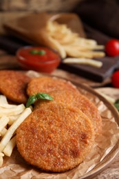 Delicious fried breaded cutlets served on wooden table, closeup