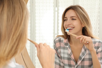 Woman brushing teeth near mirror in bathroom
