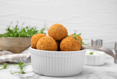Photo of Bowl of delicious fried tofu balls with pea sprouts on white marble table