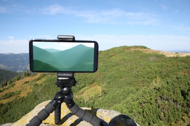 Photo of Taking video with modern phone on tripod in mountains