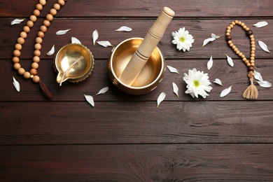 Flat lay composition with golden singing bowl on wooden table, space for text. Sound healing
