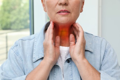 Image of Endocrine system. Mature woman doing thyroid self examination indoors