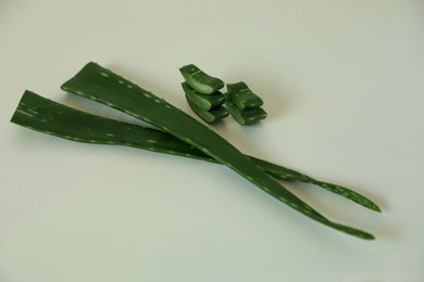 Green aloe vera leaves and slices on light background