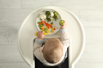 Cute little baby eating healthy food, top view