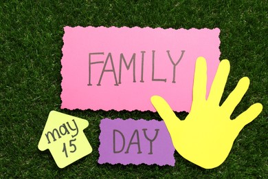 Photo of Cards with text Family Day and paper palm on green grass, flat lay